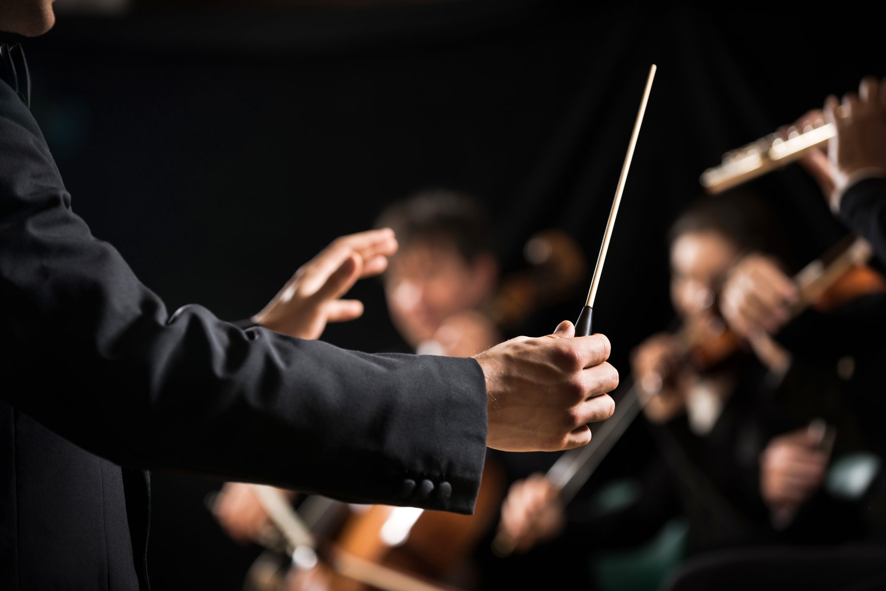 Dirigent mit Taktstock vor einem Orchester